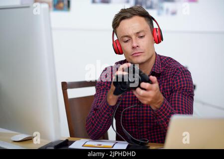 Handsome young man in headphones looking at photos in his camera Stock Photo