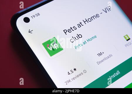 pets and home app seen in Google Play Store on the smartphone screen placed on red background. Close up photo with selective focus. Stafford, United K Stock Photo