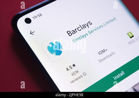 barclays app seen in Google Play Store on the smartphone screen placed on red background. Close up photo with selective focus. Stafford, United Kingdo Stock Photo