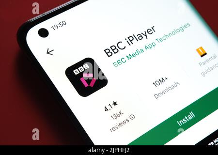 BBC iPlayer app seen in Google Play Store on the smartphone screen placed on red background. Close up photo with selective focus. Stafford, United Kin Stock Photo