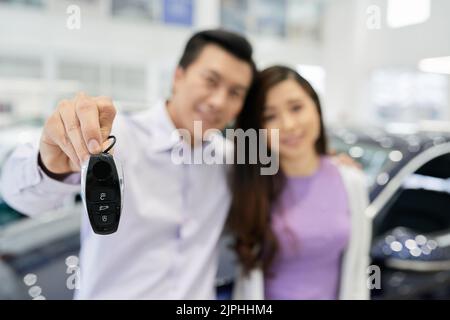 Happy couple showing keys of the car they bought, selective focus Stock Photo