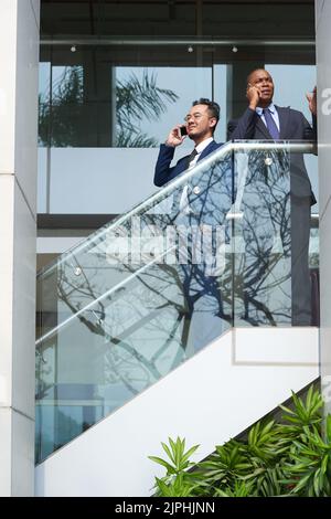 Business executives standing on stairs and talking on the phone Stock Photo