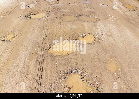 a dirt road with a lot of water holes, puddles on a dirt road after rains Stock Photo