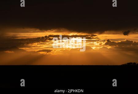 Sunset in the mountains, sunbeams in the golden sunset clouds. silhouette of the horizon Stock Photo