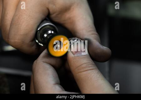 Hands of the jeweler polishes ring on the polishing machine. Goldsmith working on his workbench Stock Photo