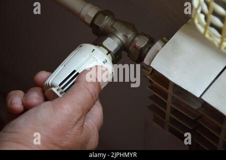 Adjusting thermostatic radiator valve to control central heating temperature Stock Photo
