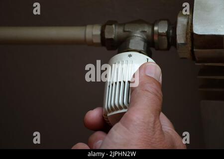 Man adjusting thermostatic radiator valve, controlling central heating temperature Stock Photo