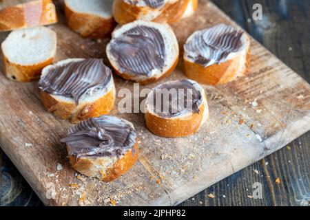 baguette with sweet chocolate butter on a board, cooking simple sandwiches with baguette and smeared with chocolate butter Stock Photo