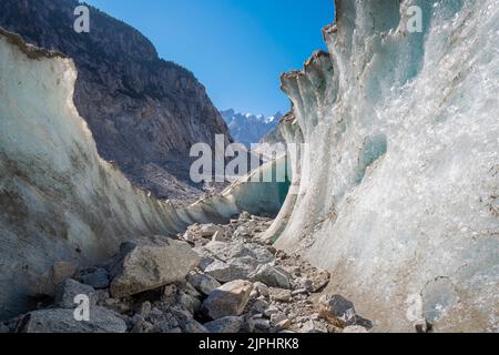 The natural glacial cave the glacier Mer de Glace with the Aiguilles towers in the background. Stock Photo
