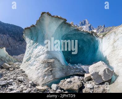 The natural glacial cave the glacier Mer de Glace with the Aiguilles towers in the background. Stock Photo