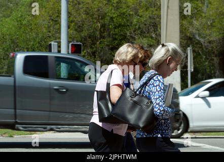 Three elderly women walking through a crosswalk on a sunny day in Jacksonville Florida Riverside area Stock Photo