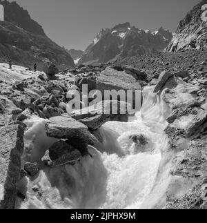 The glacial stream on the glacier Mer de Glace with the Garand Jorasses in the background. Stock Photo