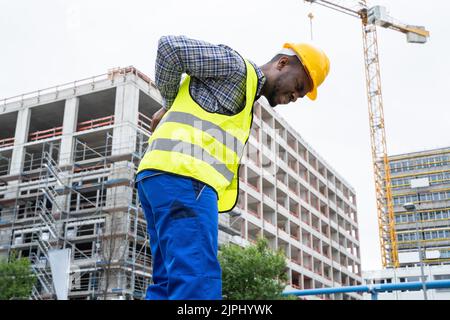 Engineer With Back Pain Injury After Accident At Construction Site Stock Photo