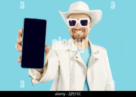 Happy young man advertising new app and showing mobile phone with empty black screen Stock Photo