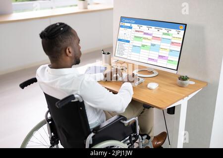 African American Looking At Agenda Using Calendar On Computer Stock Photo