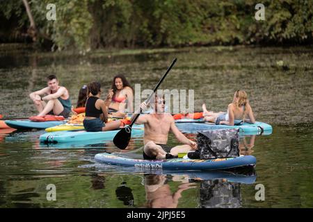 Austin Texas USA, August 14 2022: Young people relax on stand up paddleboards during a lazy summer weekend afternoon on Lady Bird Lake near downtown. ©Bob Daemmrich Stock Photo