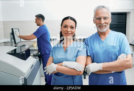 Portrait of laboratory workers with crossed arms standing in medical laboratory against background of modern laboratory research machines and equipmen Stock Photo