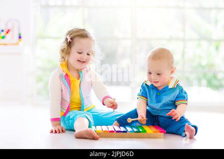 Child with colorful music instruments. Art for kids. Little girl with flute, xylophone, maracas and tambourine. Early development for children. Stock Photo