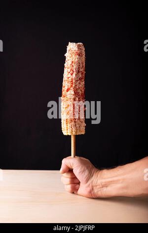 Mexican Street style corn cob are a popular street snack in Mexico, it is tender corn cooked with spices, skewered on a wooden stick covered with mayo Stock Photo