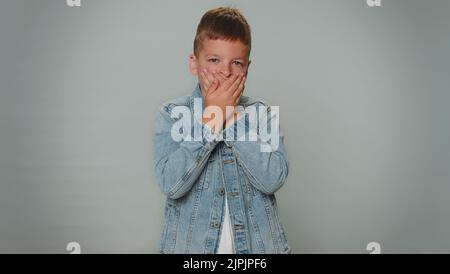 Offended toddler boy kid in jacket having misunderstanding, frustrated after quarrel, ignores and does not want to communicate, talk. Young children teenager. Child isolated on gray studio background Stock Photo