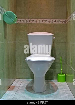 white water closet aka lavatory room, modern restroom with white ceramics toilet and green whisk on marble floor, everyday sanitary, daily hygiene, hy Stock Photo