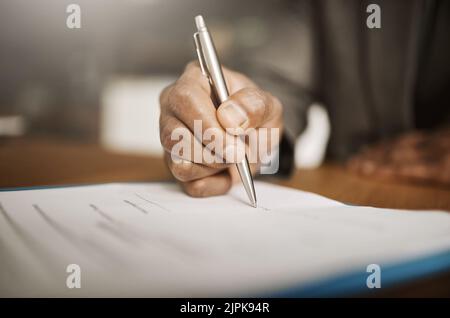 This is the first step. an unrecognizable businessperson signing papers inside of the office during the day. Stock Photo