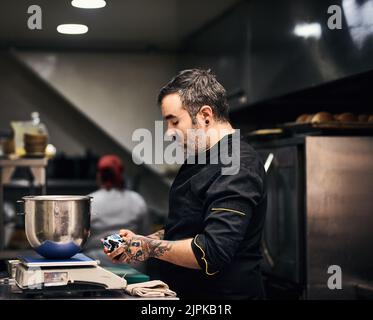 Dinner will be served shortly. a focused chef preparing a dish in the kitchen of a restaurant. Stock Photo
