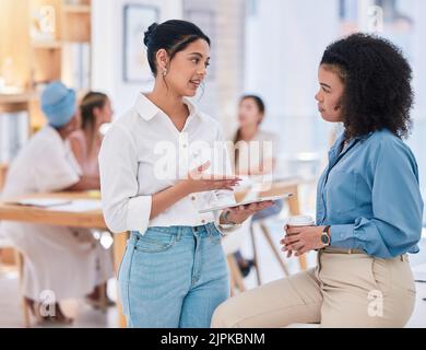 Empowered businesswomen working together on a project in the office. Female employees at work talking, collaborating, and brainstorming. Marketing Stock Photo