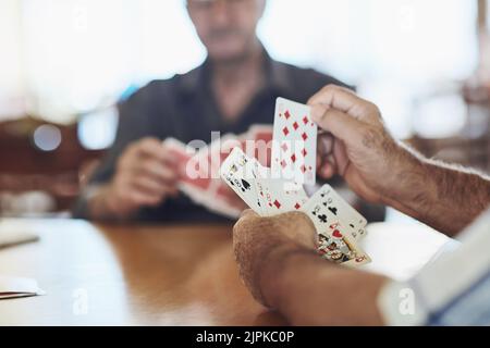 I can do something with this hand. seniors playing poker in their retirement home. Stock Photo