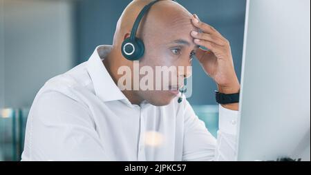 Shocked, stressed and annoyed call center agent having a bad day at work feeling unhappy and having problems. Tired, bored and frustrated male Stock Photo