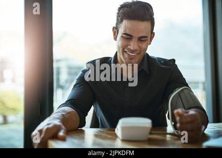 His levels are looking great. a young businessman checking his blood pressure in an office. Stock Photo