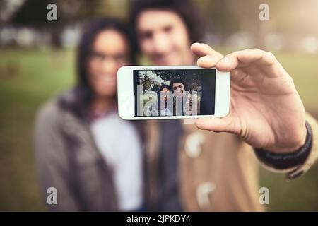 What a lovely couple. a cheerful young couple taking a self portrait together while standing outside in a park. Stock Photo