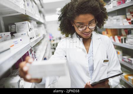 Ive been looking for this. a cheerful young female pharmacist checking stock on the shelves of a pharmacy. Stock Photo