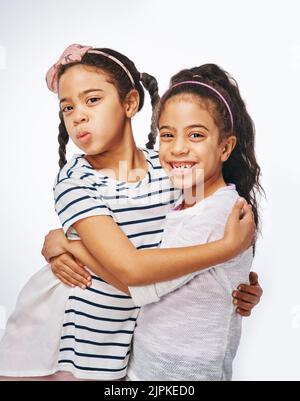 We are inseparable. two young girls embracing each other against a white background. Stock Photo