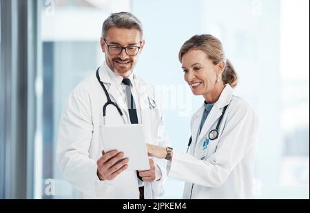 Medical, doctors and healthcare professionals working together on a digital tablet in a hospital. Portrait of a mature female and male doctor smiling Stock Photo