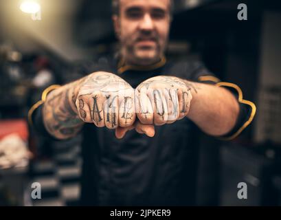 Put some love in your baking. a cheerful young chef holding up his fists to the camera with the words tattooed on them Bake Love. Stock Photo