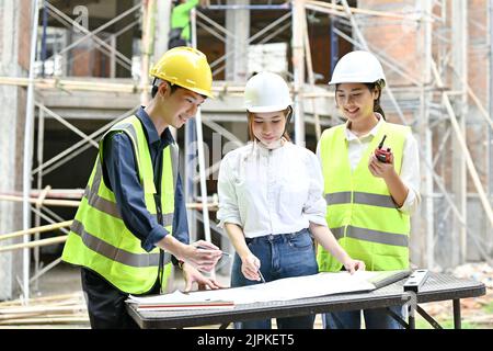 A team of civil engineers are working and inspecting the building together at the construction site. Stock Photo