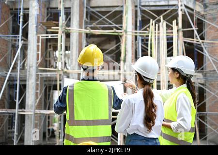 Two professional Asian female engineers are working and inspecting the building with a male construction inspector at the construction site. Civil eng Stock Photo