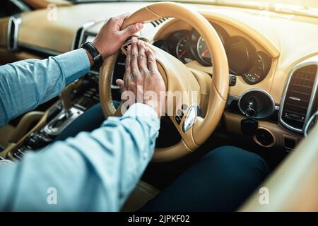 Hes getting impatient with all this traffic. Closeup shot of an unrecognisable businessman pressing the hooter on a steering wheel of a car. Stock Photo