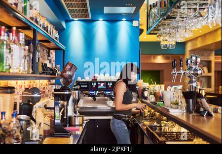 What she enjoys most. a young waitress working behind the counter at a bar. Stock Photo