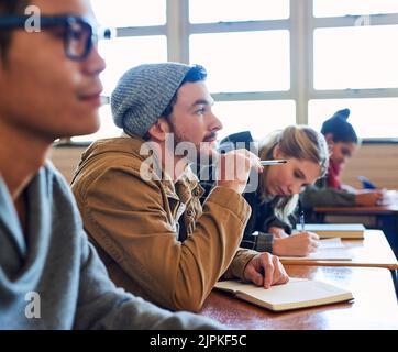 Paying full attention in class. a group of university students working in class while sitting in a lecture. Stock Photo