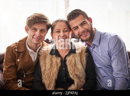 My sons outgrew my lap but never my heart. a mother and sons sitting on the sofa at home. Stock Photo