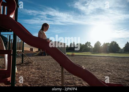 Young girl going down a slide on a playground Stock Photo