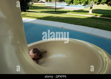 Young girl sliding down spiral slide at park Stock Photo