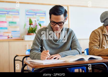 Hes a diligent student. a young male university student working in class while sitting in a lecture. Stock Photo