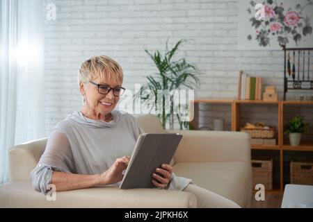 Smiling aged young woman using application on tablet computer Stock Photo