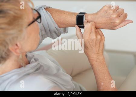 Hands of senior woman checking her smartwatch Stock Photo