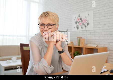Happy aged business lady working from home Stock Photo