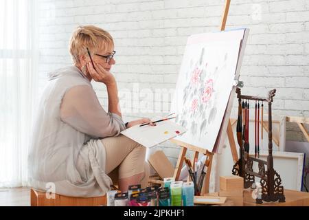 Talented creative aged woman looking at her work Stock Photo