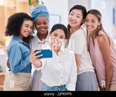 Diverse fun business friends taking selfies on a phone together in an office. Happy and beautiful colleagues or friends smiling for photos and posing Stock Photo